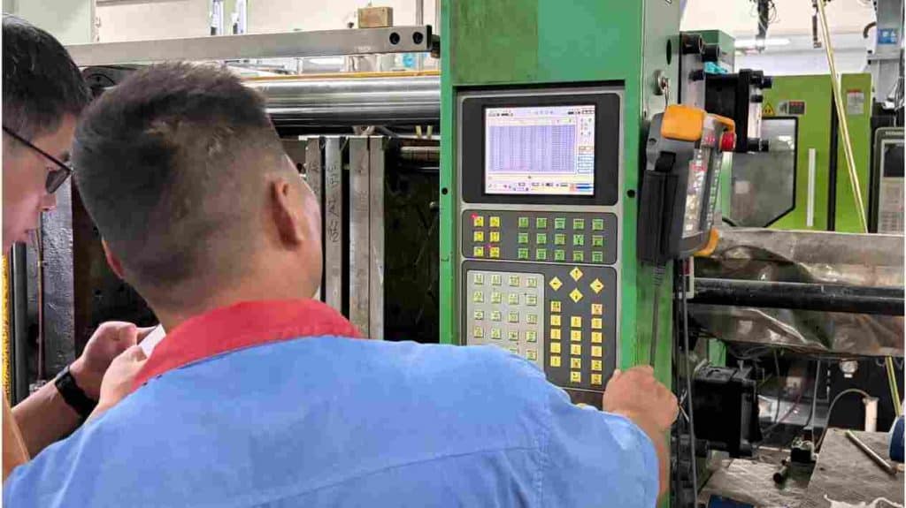 An engineer adjusting barrel temperature and back pressure at the machine control panel